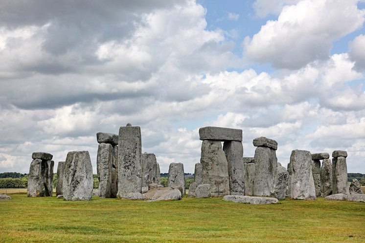 Stonehenge historic site on green grass under blue sky. Stonehen